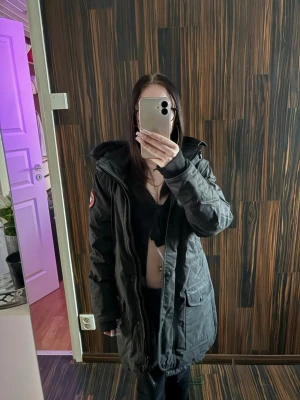 Svart jacka från Canada Goose - Säljer en svart jacka från Canada Goose den är lite sliten längst ner på armarna och sen ett litet hål inne i jackan som man ser på bilden och jackan är inte äkta 