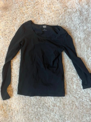 Svart långärmad topp från 157 - En enkel och stilren svart långärmad topp från 157. Toppen har rund halsringning och är tillverkad i mjuk bomull, perfekt att matcha med jeans eller kjol för en clean look.