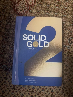 Solid Gold 2 Engelska 6 kursbok - Solid Gold 2 är en kursbok för Engelska 6 med blå och guld omslag. Boken är skriven av Eva Hedencrona, Karin Smed-Gerdin och Peter Watcyn-Jones. Perfekt för gymnasiet eller komvux och innehåller texter, övningar och grammatik.