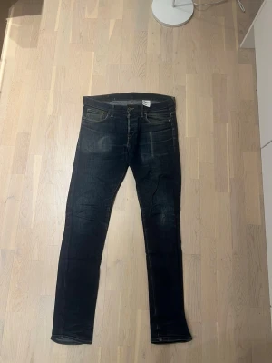 Mörkblå slim fit jeans - Snygga mörkblå slim fit jeans med klassisk femficksdesign och slitningar framtill. Jeansen har gylf med dragkedja och knapp, samt kontrastsömmar. Perfekta för en trendig och avslappnad look.