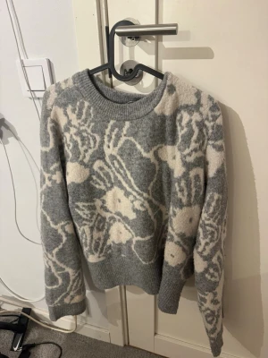 Gråvit stickad tröja Vero Moda - Mysig stickad tröja från Vero Moda i grått och vitt med ett stort fint mönster. Tröjan har rund halsringning, långa ärmar, använd 1 gång