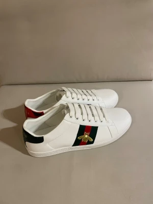 Gucci ace med bi - Snygga vita sneakers från Gucci med klassiska gröna och röda ränder på sidan och en guldbroderad bi. Storlek 42. Använd fåtal gånger men nytvättade fick de julklapp. Skriv vid frågor.