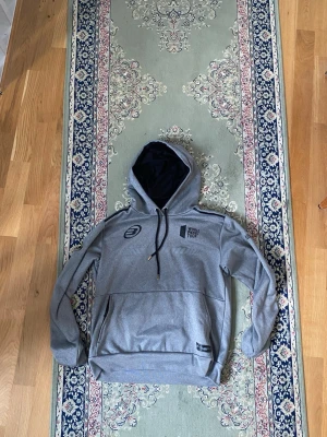 Grå hoodie med huva - En stilren grå hoodie med klassisk huva och långa ärmar. Perfekt för en avslappnad look och enkel att matcha med andra plagg. Materialet ser ut att vara mjukt och bekvämt, troligen bomullsblandning.