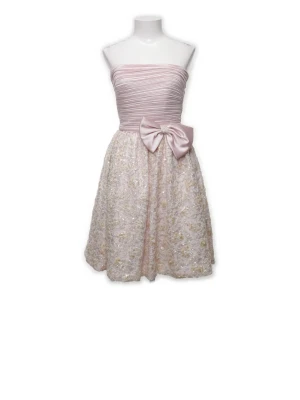 Ljusrosa axelbandslös kort klänning - Söt axelbandslös kort klänning i ljusrosa med veckad överdel och stor rosett i midjan. Kjolen är dekorerad med glittriga detaljer (handgjorda paljetter och pärlor satta på ett mönster efter spets) och har en lätt volangig känsla. Perfekt för speciella tillfällen. Köpt för 18 000 på tidigt 90 tal 