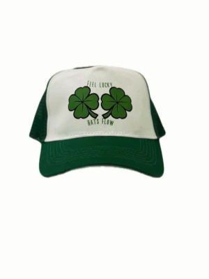 Grön och vit truckerkeps med klöver - Snygg truckerkeps från Hats Flow i grönt och vitt med mesh på sidorna och böjd skärm. Framtill finns två stora gröna fyrklöver och texten 'Feel Lucky'. Perfekt för dig som vill sticka ut med en cool accessoar.