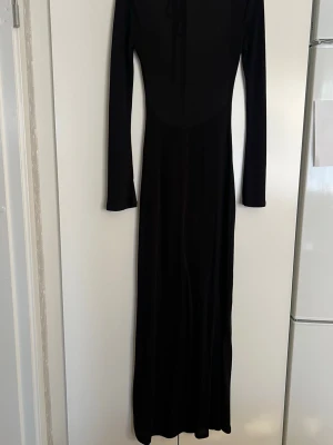 Maxiklänning med öppen rygg – Gina Tricot - Svart långklänning med öppen rygg från Gina Tricot, i ett lätt, något genomskinligt och stretchigt material. Klänningen har en mycket smickrande passform och sitter snyggt mot kroppen. Perfekt som strandklänning, semesterdress eller till somriga tillfällen – lika fin över bikini som stylad för kväll.  ✨ Använd fåtal gånger – mycket fint skick 📏 Storlek S 🎨 Färg: svart 👗 Stretchigt, lätt och följsamt material  Säljes eftersom den inte kommer till så mycket användning🥰