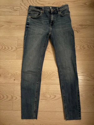 MNG Denim blå skinny jeans - Snygga blå skinny jeans från MNG Denim, modell ISA. Klassisk femficksdesign med dragkedja och knapp. Jeansen har en tvättad look och smal passform som sitter tajt längs benen. Perfekta till en avslappnad streetstyle eller casual outfit.