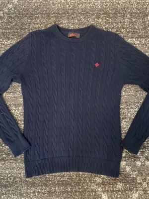 Mörkblå Kabelstickad Tröja Morris - Säljer min stickade Morris tröja i storlek L men passar M. Den är i bra skick och har inga tecken på slitage.
