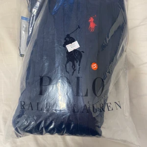 Marinblå kabelstickad tröja Polo Ralph Lauren - Säljer en marinblå kabelstickad tröja från Polo Ralph Lauren. Tröjan har rund halsringning, långa ärmar och den klassiska röda logotypen broderad på bröstet. Perfekt för dig som gillar stilrena och tidlösa plagg.