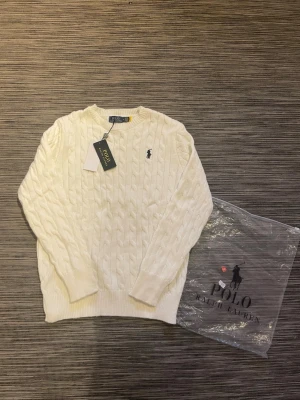 Vit kabelstickad tröja Polo Ralph Lauren - Säljer en stilren och snygg polo Ralph Lauren tröja! Tröjan är helt ny, aldrig använd. Qr-Koden funkar som den ska. Om ni har några frågor så är de bara att höra av er!😃