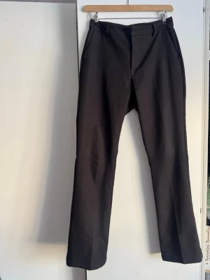 Svarta kostymbyxor från BikBok - Stilrena svarta kostymbyxor från BikBok med raka ben och klassisk passform. Byxorna har hällor för skärp och diskret knäppning framtill. Perfekta för en clean och snygg look.