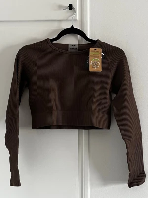 Macchiato ribbed seamless croptop från aim'n - Snygg brun/macchiato långärmad crop top från aim'n. Strechigt ribbat material. Ny och oanvänd med lappar kvar. 