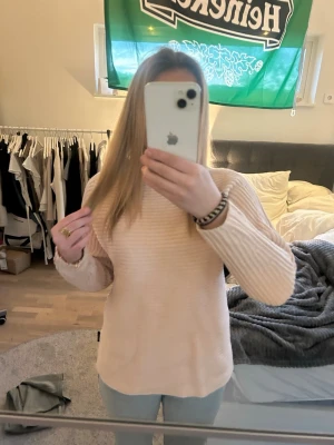 Ljusrosa stickad tröja - Mysig ljusrosa stickad tröja med rund hals och diskret ribbad struktur. Tröjan har långa ärmar och en rak passform som gör den enkel att styla till olika outfits. Perfekt för dig som gillar en enkel men snygg look.