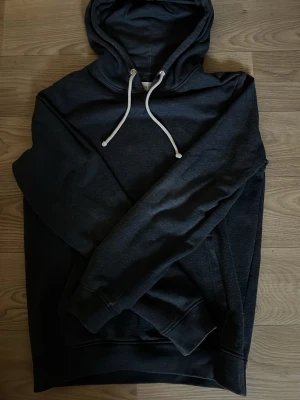 Pier one hoodie - En stilren svart hoodie med huva och vita dragsnören. Klassisk passform och mjukt material som känns skönt mot huden. Perfekt för dig som gillar en enkel men snygg look. Inga synliga loggor eller tryck, bara clean design. Hör va er vid frågor eller om ni vill ha fler bilder!