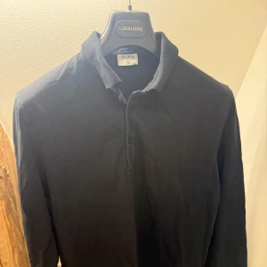 Svart långärmad skjorta Filippa K - Klassisk svart långärmad skjorta från Filippa K med krage och knappar framtill. Tillverkad i mjukt bomullstyg som känns skönt mot huden. Enkel och stilren design som passar till det mesta. Köpt på NK, nypris 1799kr