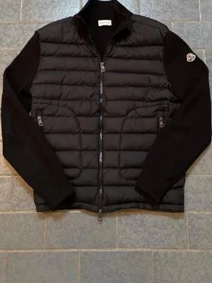 Moncler cardigan  - Snygg svart dunväst från Moncler med quilt alike mönster och dragkedja framt sexually. VästenBröstet har två fickor med dragkedja och Moncler-logga på ärmen. Säljer pga att den inte passade min kille 