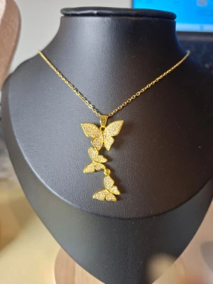 Guldigt halsband med stjärnhänge - Snyggt halsband i guldfärgad metall med ett stjärnformat hänge. Kedjan är tunn och elegant, perfekt för att ge en extra touch till din outfit. Hänget har en glittrande yta som fångar ljuset fint.