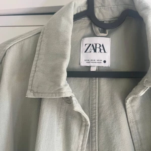 Grön kappa från Zara  - Säljer en grön kappa från Zara. Aldrig använd!! Så i princip ny. Jacka har knäppning med  knappar och är tillverkad i ett kraftigare bomullstyg. Perfekt att slänga över en t-shirt på en sommarkväll. Hör av er via frågor eller funderingar!🤍