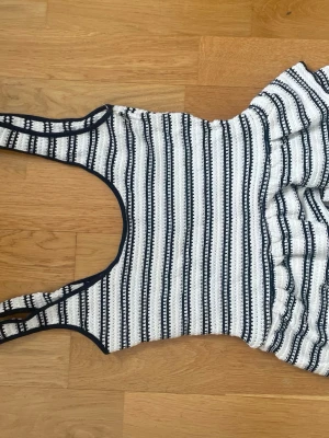 Randig vit och svart linnetopp - Säljer en snygg randig linnetopp i vitt och svart med breda axelband och rundad halsringning. 