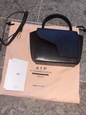 ATP väska  - Säljer denna supersnygga, väska från ATP. Den är sparsamt använd och i väldigt bra skick. Axelband, påsen till väskan ingår❤️❤️Det är den minsta storleken och nypris är 3900kr färg: Black 