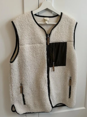 Vit teddyväst från H&M  - Mysig vit teddyväst från H&M med gröna detaljer. Perfekt nu till våren eller på afterskin 😊