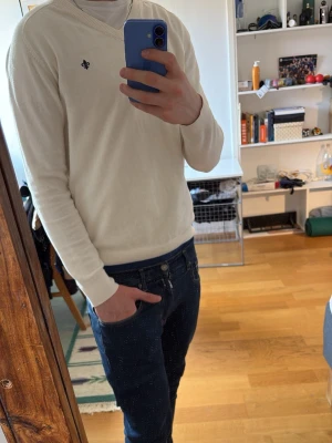 Vit tröja från Morris - Klassisk vit tröja från Morris med diskret logga broderad på bröstet. Tröjan har långa ärmar, ribbade muddar och är tillverkad i ett tunt, mjukt material som känns skönt mot huden. Perfekt för en clean och stilren look inför våren. 