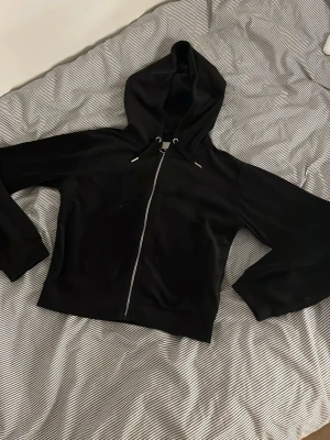 Svart hoodie med dragkedja - Svart hoodie med dragkedja framtill och huva med snören. Klassisk modell med långa ärmar och ribbade muddar. Perfekt för en chill och avslappnad stil.