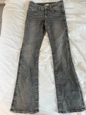 Grå bootcut jeans från Gina Tricot - Snygga grå jeans från Gina Tricot i bootcut-modell. Jeansen har klassisk femficksdesign, normal passform och är tillverkade i mjukt denimtyg. Perfekta för dig som gillar en avslappnad men trendig look.