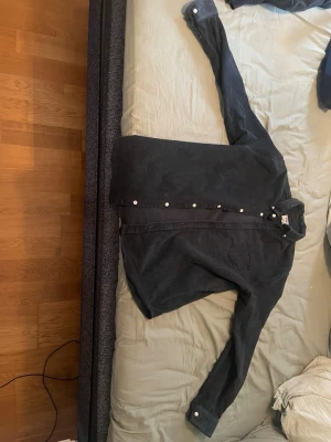 Mörkblå manchesterskjorta från Rebel - Mörkblå manchesterskjorta från Rebel med klassisk krage och vita knappar. Skjortan har lång ärm och är gjord i mjuk manchester