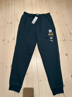 Sköna gröna mjukisar från Puma - Jag säljer ett par bekväma gröna mjukisar i storlek L som köptes för 630kr. De har ett snyggt vitt och guldigt tryck på vänster ben. Helt oanvända, pris kan diskuteras🤗