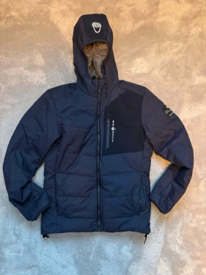 Sail Racing Patrol Down Jacka - Säljer min Sail Racing Patrol Down Jacket, en lätt och varm dunjacka perfekt för segling, friluftsliv eller vardagsbruk. Jackan är sparsamt använd och i gott skick. Nypris låg runt 5 500 kr, vilket gör detta till ett riktigt bra tillfälle att få en kvalitetsjacka till ett betydligt lägre pris.