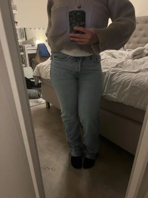 Ljusblå raka jeans - Säljer ett par ljusblå jeans med rak passform och klassisk femficksdesign. Jeansen har hög midja och är tillverkade i ett mjukt denimtyg. Perfekta för en avslappnad och trendig look. Passar dig som gillar en enkel och stilren stil.