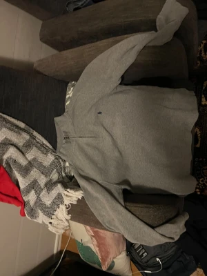 Grå halvzip tröja från Ralph Lauren - Snygg grå tröja från Ralph Lauren med halv dragkedja och klassisk blå logga broderad på bröstet. Tillverkad i mjukt stickat material och har hög krage. Perfekt för lager på lager och enkel att matcha med olika outfits.