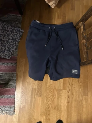 Mörkblå shorts från Hugo Boss  - Mörkblå shorts från Hugo Boss med metall snörning i midjan och en diskret logga på vänster ben. Perfekta inför sommaren.