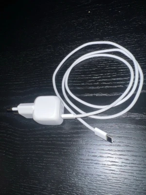 Belkin 20W USB-C laddare med kabel - Säljer en vit Belkin 20W USB-C väggladdare med tillhörande flätad USB-C till USB-C kabel. Laddaren har en kompakt och fyrkantig design och kabeln är tålig med textilöverdrag. Perfekt för snabbladdning av mobiltelefoner och andra enheter.