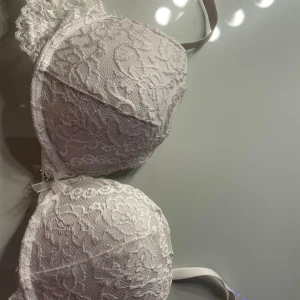 Vit spets-bh med rosett och hänge - Säljer en vit push up bh från cubus  med vadderade kupor och vacker spets över hela ytan. storlek 75A💕 Mellan kuporna sitter en liten rosett och ett silverfärgat hänge med bokstäverna 'SB'. Justerbara axelband och klassisk hakknäppning bak. 