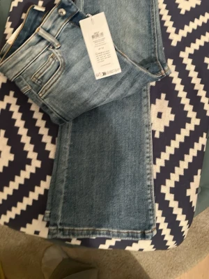  ONLY Blå flared jeans   - Snygga blå jeans från Only / flared och klassisk femficksmodell. Jeansen har en ljus tvätt och subtila slitningar framtill. Perfekta för en avslappnad och trendig look. 27/32 