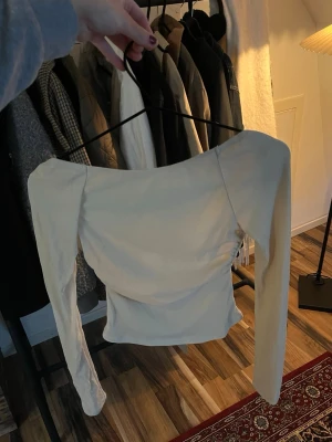 Beige & guld-glittring långärmad topp med öppen rygg - Trendig  beige topp med guld-glitter detaljer med lång ärm och öppen rygg. Snygg croppad passform som framhäver axlarna. Perfekt på fest eller liknande. 