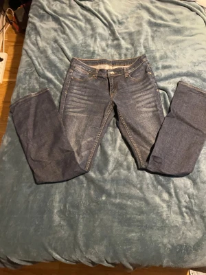 Blå jeans från Twilfit - Säljer ett par klassiska blå jeans, med raka ben och. Jeansen har snygga slitningar framtill och kontrastsömmar i gult. Tillverkade i slitstarkt denimtyg som passar perfekt till en avslappnad stil.