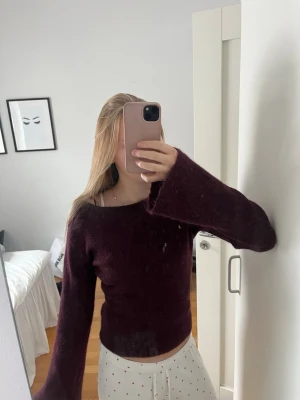 Vinröd stickad tröja Gina Tricot - Mysig vinröd stickad tröja från Gina Tricot med bred halsringning och långa, vida ärmar. Tröjan har en fluffig och mjuk struktur som ger en avslappnad look. Perfekt att matcha med jeans eller kjol för en trendig outfit.💕