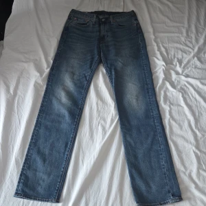 Blå raka jeans från Levi's, lot 514 - Klassiska blå jeans från Levi's med rak passform och fem fickor. Jeansen har en snygg tvätt med lätt slitning på låren och är tillverkade i denim. Perfekta för en avslappnad och stilren look.