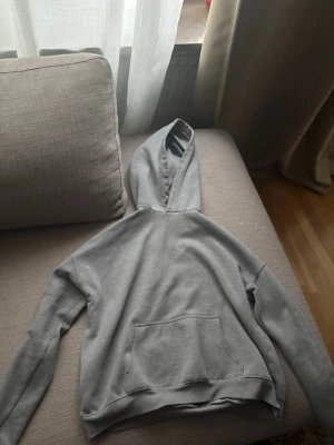 Grå hoodie med röd text TROUBLE - Grå hoodie med huva och magficka. På bröstet står det. Du kan vända hoodien back och fram med huvan.