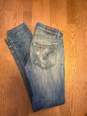 Dondup George jeans - Säljer ett par blå jeans från dundup med snyggt slitna detaljer och klassisk femficksmodell. De är i storlek 33 men sitter snarare som 28-29 Jeansen har en ljus tvätt och raka ben, samt coola kontrastsömmar på bakfickan. Perfekta för en avslappnad och trendig look. Den har gått upp vid gylfen men är lagat och syns inte väl på