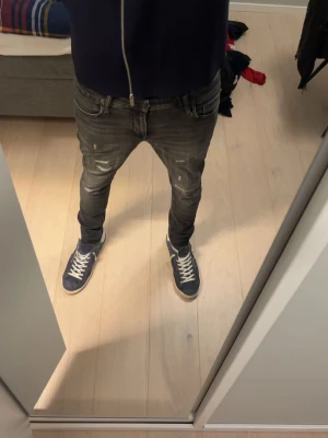 Svarta slim fit jeans med slitningar - Snygga svarta slim fit jeans med coola slitningar och tvättade detaljer. Jeansen har klassisk femficksdesign och låg midja. Perfekta för en avslappnad streetstil.