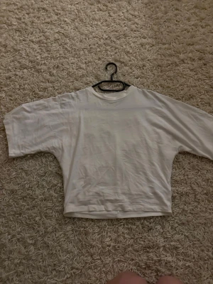 Vit oversized t-shirt från 157 - En vit oversized t-shirt från 157 med rund hals och korta ärmar. Tillverkad i mjuk bomull som känns skön mot huden. Enkel och clean design som passar till allt. Perfekt för dig som gillar en avslappnad och trendig stil.