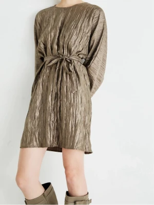 Beige omlottklänning med knytband - Säljer en beige kortklänning med crinkle-effekt och knytband i midjan. Klänningen har lång ärm och rund halsringning, samt en avslappnad passform. Perfekt för dig som gillar en unik och trendig look.