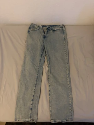 Ljusblå raka jeans - Säljer ett par ljusblå jeans med rak passform och klassisk femficksdesign. Jeansen har normal midja och är tillverkade i denim. Perfekta för en avslappnad och trendig stil.