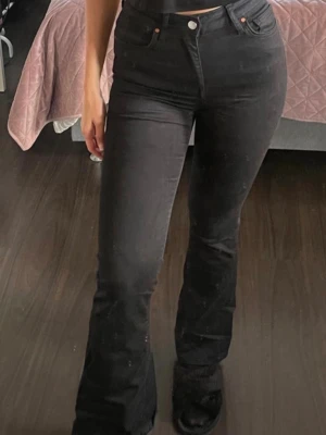 Svarta Peachy Flare jeans - Säljer ett par svarta Peachy Flare jeans med hög midja och utsvängda ben. Jeansen har klassisk femficksdesign, knapp- och dragkedjestängning samt längd 33. Perfekta för dig som gillar en trendig och bekväm passform.