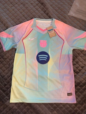 Barcelona Nike matchtröja pastell - Säljer en Barcelona matchtröja från Nike i pastellfärger med rosa, blått och gult. Tröjan har klubbmärke och Nike-logga på bröstet samt Spotify-logga i mitten. Tillverkad i lätt och ventilerande funktionsmaterial, perfekt för träning eller match.