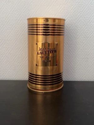 Jean Paul Gaultier Le Male Elixir - Lyxig parfym i guldigt metallhölje från Jean Paul Gaultier, Le Male Elixir. Flaskan har en unik kroppsliknande form med horisontella ränder och levereras i en matchande guldfärgad burk. Perfekt för dig som gillar exklusiva dofter och snygg design.